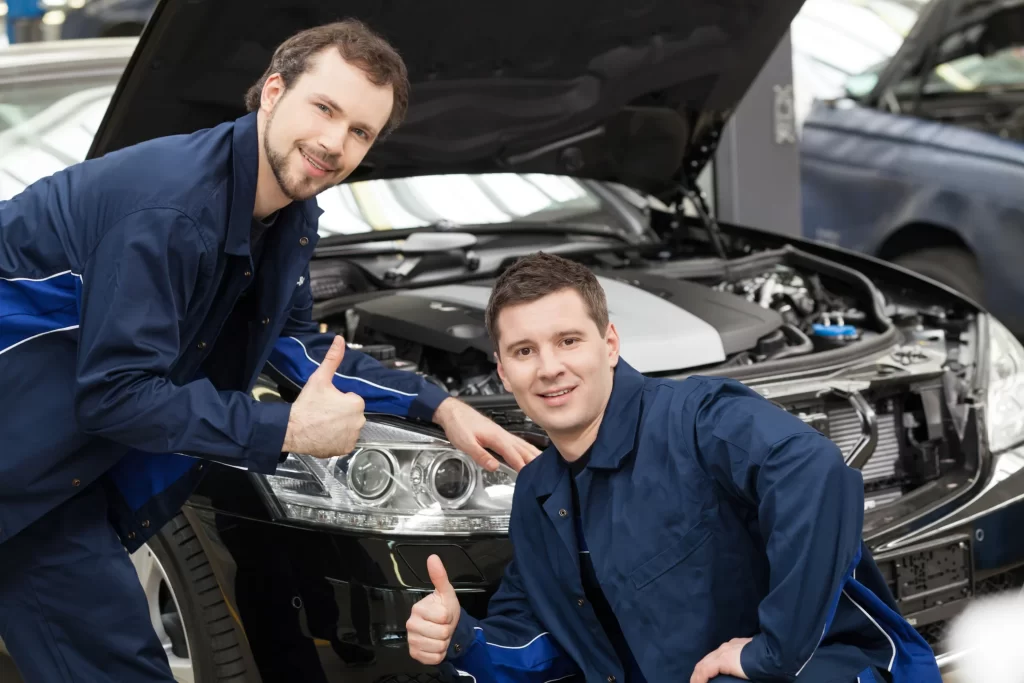 Two mechanics smiling and posing at the camera.