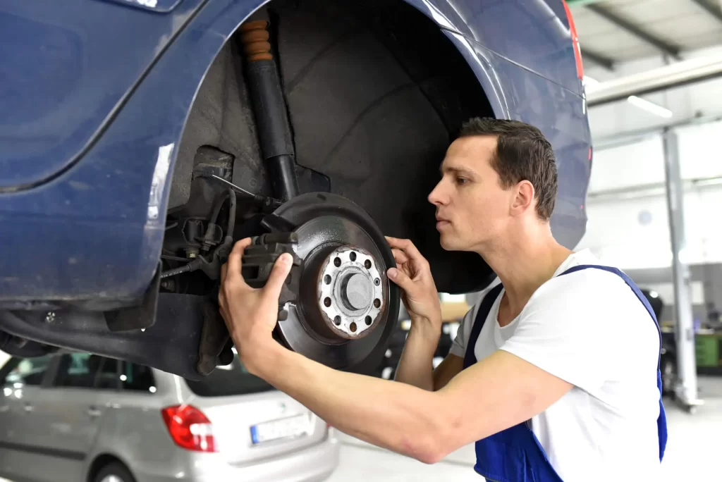 An auto mechanic working on braking system repair at an auto repair facility.