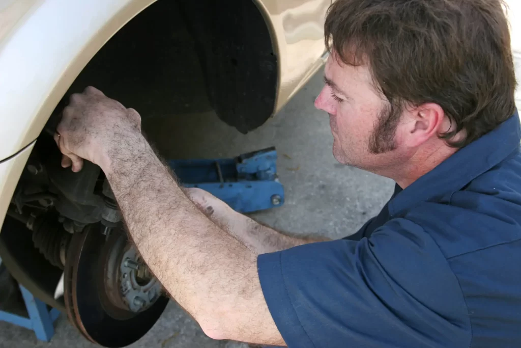 An auto mechanic working on a car's brakes.