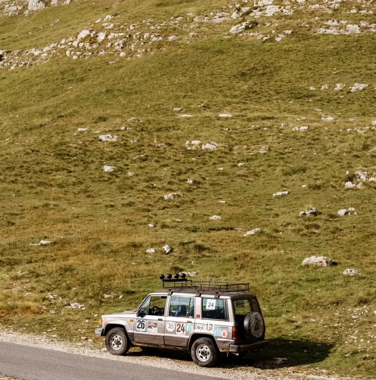 An Isuzu Trooper with stickers parked on the side of a mountain.
