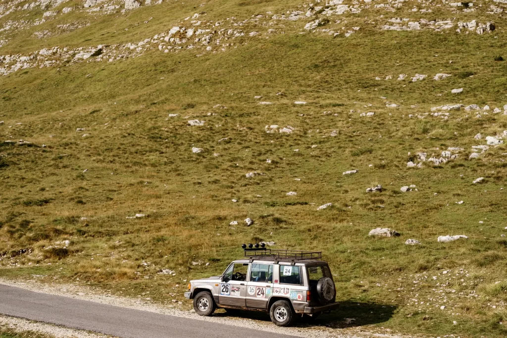 An Isuzu Trooper with stickers parked on the side of a mountain.