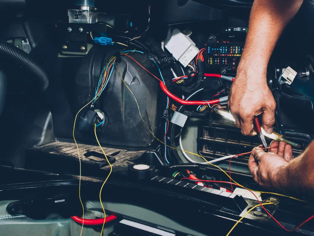 An auto mechanic repairing an electrical system's wiring.