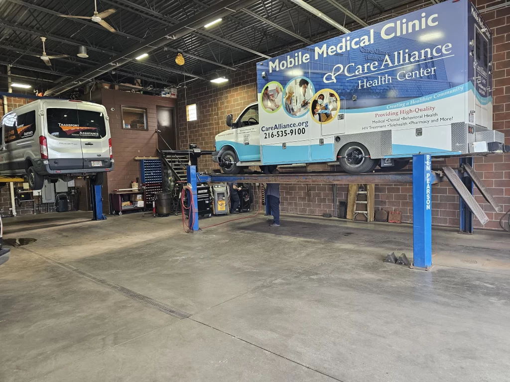 Parma Car Care service bay with a mobile medical clinic and a van on hydraulic lifts for maintenance.