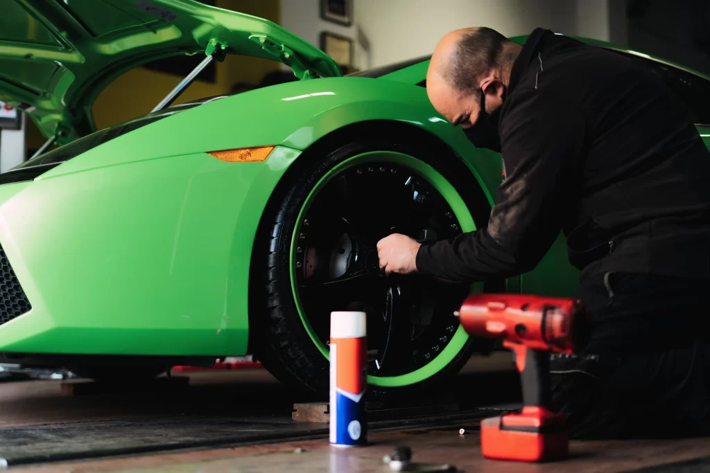 A car mechanic changing the wheels of a high-end sports car at a garage.