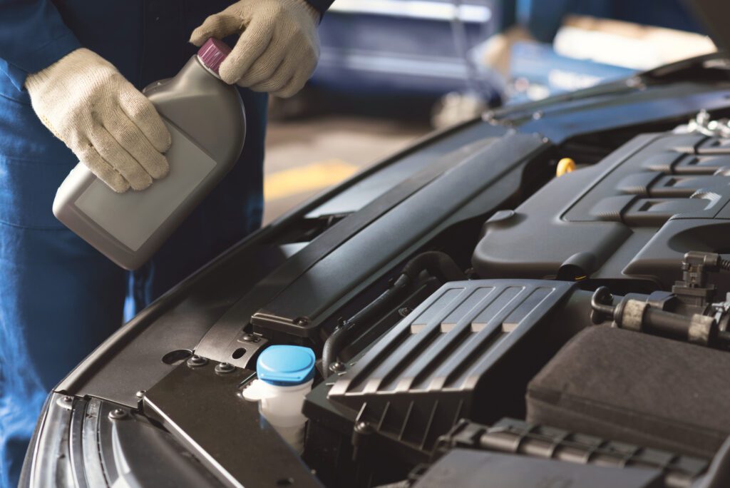 Auto mechanic performing a maintenance procedure and using specific fluid for making the car working better.