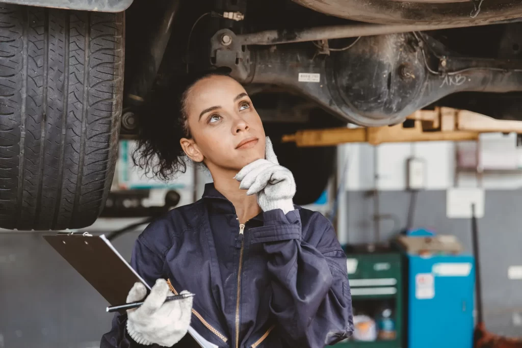A female car mechanic thinking while working on under-car repair servies.