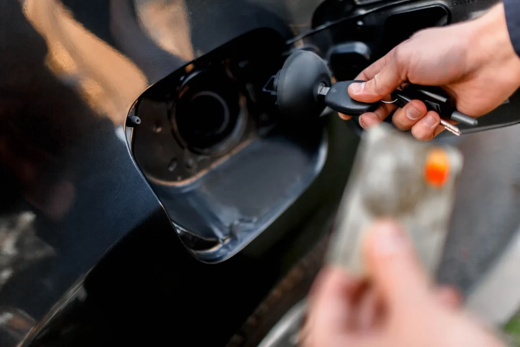 Man with credit card opening fuel tank of his new car.